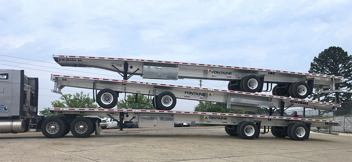 A stacked arrangement of aluminum trailers is securely loaded onto a truck, showcasing their sleek design and shiny finish.