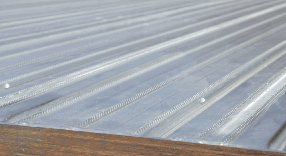 A close-up view showcases a metallic surface with parallel ridges and a wooden edge.